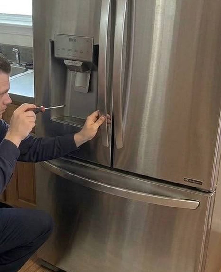 Ice and water dispenser under screwdriver on an LG refrigerator